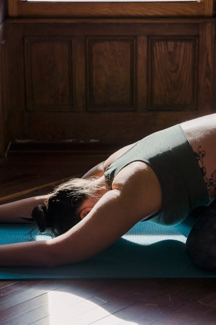 Woman gracefully stretching during a morning yoga routine in a sunlit room.