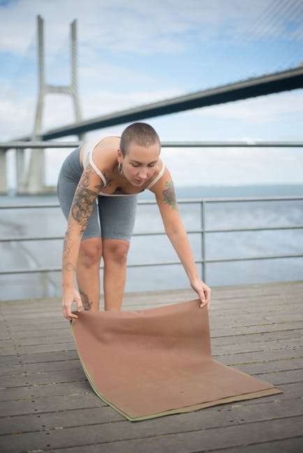 Woman in a peaceful lotus pose enjoying the sunrise on a wooden deck.